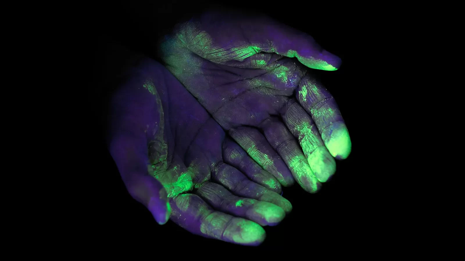 image of hands with uv light illuminating the germs on the hands